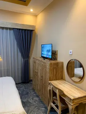 a bedroom with a bed and a tv and a table at Pradantara House in Nusa Dua