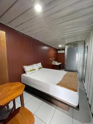 a bedroom with a bed and a wooden wall at trees inn Bali Denpasar in Denpasar