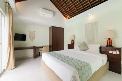a bedroom with a bed and a desk and a television at Tan's Astana Villa's by The Lavana in Seminyak