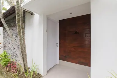 a hallway with a wooden door in a house at Tan's Astana Villa's by The Lavana in Seminyak