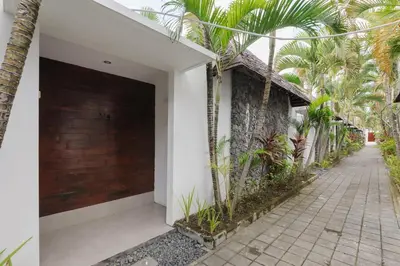 a building with a wooden garage door and palm trees at Tan's Astana Villa's by The Lavana in Seminyak