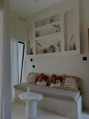 a room with a bench with pillows and a table at Shine sunset villa in Kerobokan