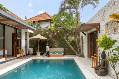 a woman standing in front of a house with a swimming pool at Villa Tropea by BaliSuperHost in Seminyak