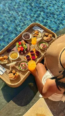a woman laying on a tray of food next to a pool at Anathera Resort Kuta Bali Airport in Kuta