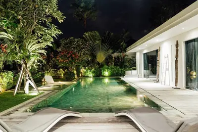 a swimming pool in the backyard of a house at night at Seminyak villa 3 chambres service 5 in Seminyak