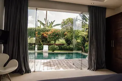 a room with a large window with a swimming pool at Seminyak villa 3 chambres service 5 in Seminyak