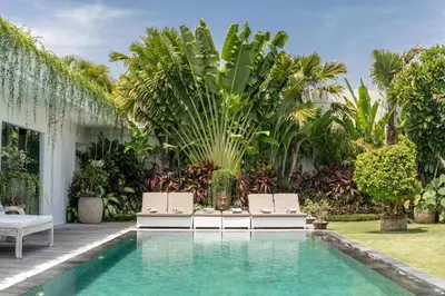 a swimming pool with two lounge chairs next to a house at Amazing 4 BR villa with garden, pool in Seminyak in Seminyak