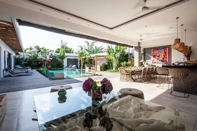 a living room with a glass table and a pool at Seminyak 5 bd villa avec Chill-out extérieur in Seminyak