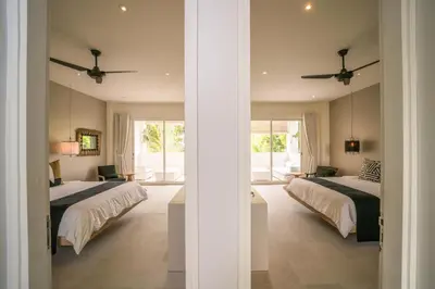 a bedroom with two beds and a room with windows at 4BR Group Holiday, Walk to Fitness, Food, Beach in Seminyak