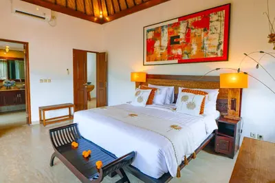 a bedroom with a large bed and a bench at Villa Leona Seminyak in Seminyak