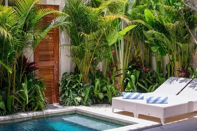 a pool with a chair and a couch next to a garden at Beautiful 1 bedroom villa in perfect location in Seminyak