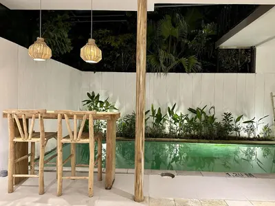 a wooden table and chair next to a pool at Spring Villa Nusa Dua in Nusa Dua