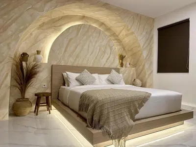a bedroom with a large bed with a stone wall at Spring Villa Nusa Dua in Nusa Dua