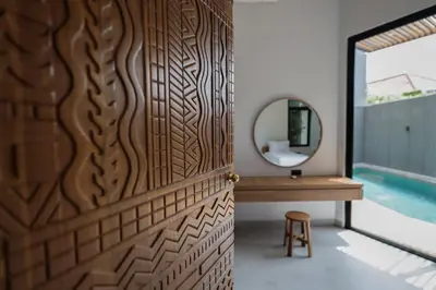 a bathroom with a wooden door and a mirror at Rumah Christa in Seminyak