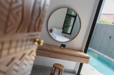 a mirror sitting on a table next to a bed at Rumah Christa in Seminyak