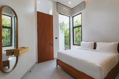 a bedroom with a bed and a mirror and windows at Rumah Christa in Seminyak