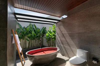 a bathroom with a large stone tub next to a toilet at D'Padi Villa Canggu in Canggu