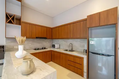 a kitchen with wooden cabinets and a vase on a counter at Sunterra 3- Luxurious 3BR Villa in Canggu with Pool in Kerobokan