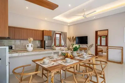 a kitchen and living room with a wooden table and chairs at Sunterra 3- Luxurious 3BR Villa in Canggu with Pool in Kerobokan