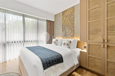 a bedroom with a large bed and a large window at Calira by Kozystay - Nusa Dua in Nusa Dua