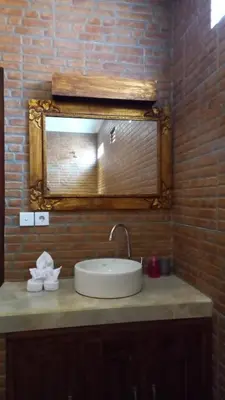 a bathroom sink with a mirror on a brick wall at Ben & B villa in Kerobokan