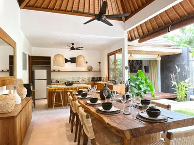 an open kitchen and dining room with a large wooden table at Villa Pacha Seminyak in Seminyak