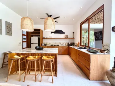 a kitchen with a large wooden table and stools at Villa Pacha Seminyak in Seminyak