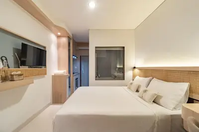 a bedroom with a large white bed and a tv at The Hita Uluwatu in Jimbaran