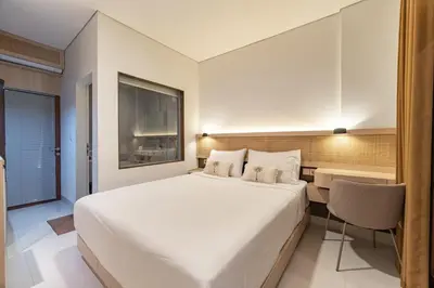 a bedroom with a large white bed and a desk at The Hita Uluwatu in Jimbaran
