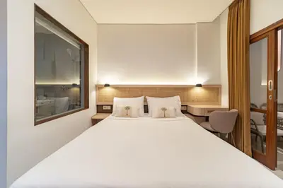 a bedroom with a large white bed and a desk at The Hita Uluwatu in Jimbaran