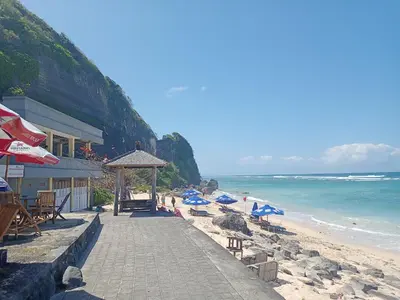 a beach with chairs and umbrellas and the ocean at Designer Alex Villa Jimbaran Bali in Jimbaran