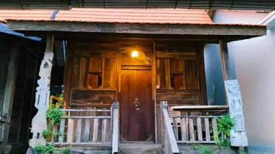a house with a wooden door and a table at Queen's Cabin in Kerobokan