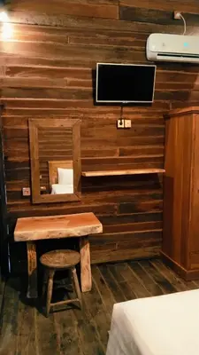 a room with a wooden wall with a bench and a tv at Queen's Cabin in Kerobokan