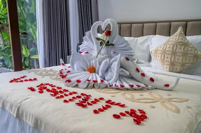 a bed with white towels and flowers on it at Villa Shinta by JB Villas in Seminyak