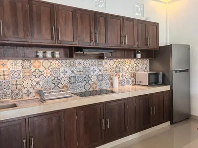 a kitchen with wooden cabinets and a stainless steel refrigerator at Villa Veyla Seminyak 10 mins walk to beach in Seminyak