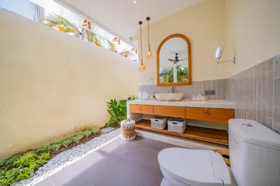 a bathroom with a toilet and a sink and a mirror at Luxury Balinese Oasis with private pool - 2 BR in Kerobokan