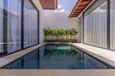 an indoor swimming pool in a house with windows at Villa Fénix Brand New 1BR Villa in Umalas, Bali in Kerobokan