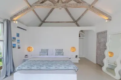 a bedroom with a white bed and wooden ceilings at Villa Cocodrilos 1 by Pertama Management in Seminyak