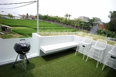 a grill and chairs on a balcony with grass at The Cendana Villa Umalas in Badung
