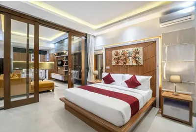 a bedroom with a large bed and a living room at Puri Sahadewa Seminyak in Seminyak