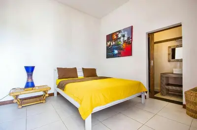 a bedroom with a yellow bed and a table at Villa Langit Ocean View Jimbaran in Jimbaran