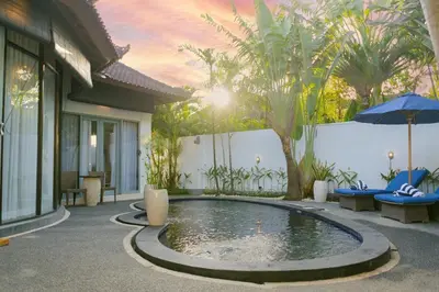 a pool in front of a house with an umbrella at Peaceful 2br with pool & garden in Seminyak