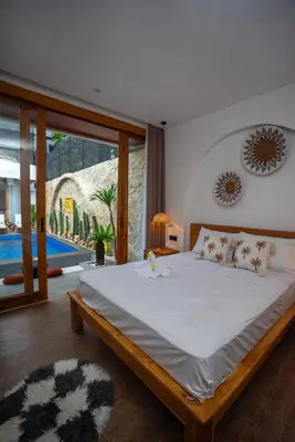 a bedroom with a large bed and a pool at Zahra Villas in Nusa Dua