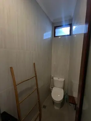 a small bathroom with a toilet and a window at Modern 3BR Villa with Private Pool & Rooftop in Nusa Dua in Nusa Dua