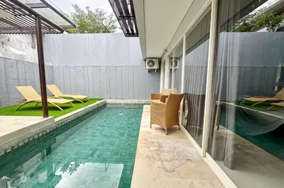 a swimming pool with chairs next to a house at Green Leaf Villa - 1 Bedroom pool Villa with Minimum Stay 2 Nights in Nusa Dua