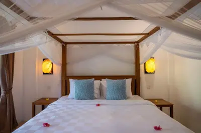 a bedroom with a white bed with blue pillows at Genta- Petitenget 2BR villa, walk to beach! in Seminyak