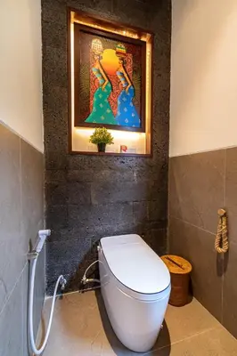 a bathroom with a toilet and a painting on the wall at Villa Bolon in Kuta