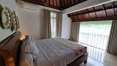 a bedroom with a bed and a large window at 2 Minutes Walk to the Beach 3BR Retreat Villa in Canggu