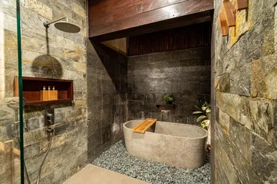 a bathroom with a bath tub in a stone wall at Villa Dijabu in Kuta