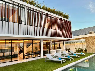 an external view of a house with lounge chairs and a pool at Villa Kawis Seminyak in Seminyak